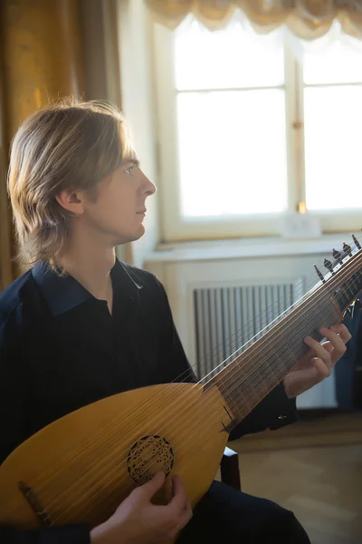 Schöner junger Mann spielt antike Laute — Stockfoto