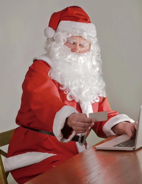 Papai Noel usando seu cartão de crédito para comprar online — Fotografia de Stock