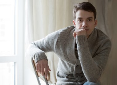 pencerenin oturan örgü ceket giyen adam