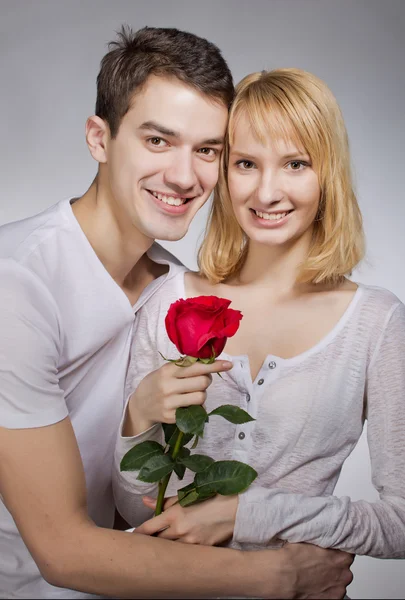 Ungt par älskare. Man presenterar röd ros för alla hjärtans dag. — Stockfoto