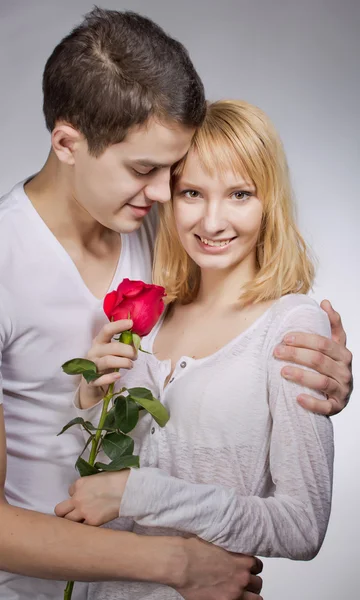 Jonge paar liefhebbers. Man presenteert rode roos voor dag van de Valentijnskaart. — Stockfoto