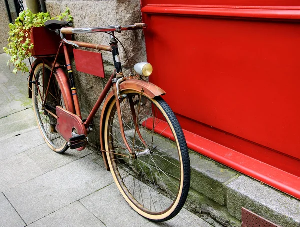 Bicicleta vermelha vintage inclinada na placa de madeira vermelha — Fotografia de Stock