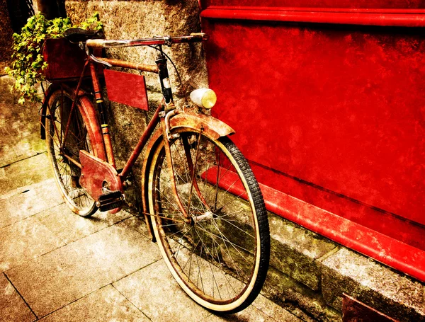 Bicicleta vermelha vintage inclinada na placa de madeira vermelha — Fotografia de Stock