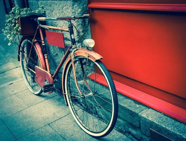 Bicicletta rossa vintage appoggiata su tavola di legno rossa Immagine Stock