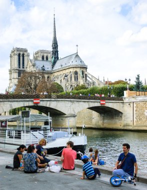 Tourists have picnic near Notre Dame Cathedral. clipart