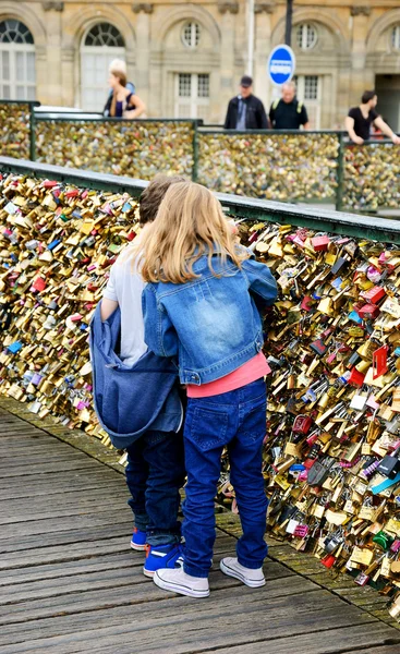 Boy and girl on Love locks bridge in Paris. — Stock Photo, Image