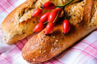 Çok eski bir damalı havlu üzerinde tahıl ekmeği fırından yeni çıkmış. Rustik tarzı. Rose hips ekmek arasında tarih seçici odak.