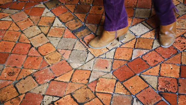 Closeup of young woman legs in motion on terracotta tile floor in old house. — Stock Photo, Image