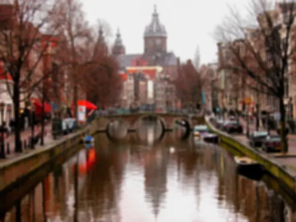 Průplav Amsterdam s mostem a výhledem na baziliku svatého Mikuláše (Sint-Nicolaasbasiliek) se jeho odraz na vodě. Rozmazané tónovaný fotografie. — Stock fotografie