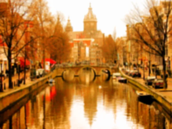 Průplav Amsterdam s mostem a výhledem na baziliku svatého Mikuláše (Sint-Nicolaasbasiliek) se jeho odraz na vodě. Rozmazané tónovaný fotografie. — Stock fotografie