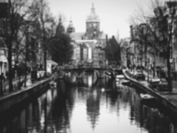 Canal de Ámsterdam con puente y vistas a la Basílica de San Nicolás (Sint-Nicolaasbasiliek) con su reflexión sobre el agua. Foto tonificada borrosa. Blanco y negro . — Foto de Stock