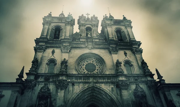 Het Alcobaca klooster in sombere bewolkte dag. Middeleeuws rooms-katholiek klooster in Alcobaca (Portugal) is UNESCO werelderfgoed. Zon lichtstralen door de wolken. Retro leeftijd gestemde foto. — Stockfoto