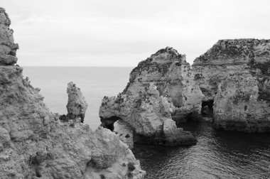 Taş kemer, mağaralar, kaya oluşumları Dona Ana Beach (Lagos, Algarve kıyısında, Portekiz) akşam ışık. Yaşlı fotoğraf. Siyah ve beyaz.