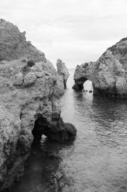 Taş kemer, mağaralar, kaya oluşumları Dona Ana Beach (Lagos, Algarve kıyısında, Portekiz) akşam ışık. Yaşlı fotoğraf. Siyah ve beyaz.