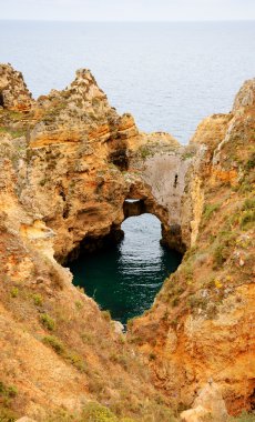 Okyanus su taşları delikten gördün. Taş kemer, mağaralar, kaya oluşumları Dona Ana Beach (Lagos, Algarve kıyısında, Portekiz) akşam ışık.