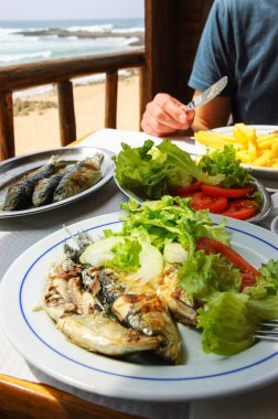 Geleneksel Portekizce - ızgara sardalya - okyanus plaj manzaralı Teras Restoran, öğle yemeği. Algarve, Portekiz.