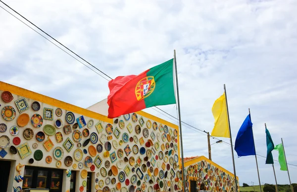 ALGARVE, PORTOGALLO - 3 MAGGIO 2015: Piatti tradizionali in ceramica colorata sulla parete del locale negozio di ceramiche e bandiera portoghese. L'Algarve è famosa per le sue ceramiche dipinte a mano e ceramiche . — Foto Stock