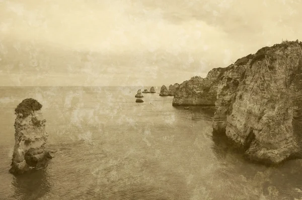 Nádherné skalní útvary, kamenné oblouky a jeskyně na Dona Ana Beach a plachetnice na obzoru (pobřeží Lagos, Algarve, Portugalsko) ve večerním světle. Retro věku sepia fotografie s škrábance. — Stock fotografie