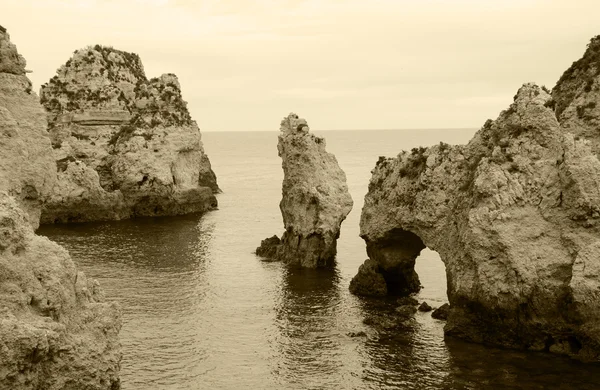 A kő boltozatok, barlangok, sziklaalakzatok: Dona Ana Beach (Lagos, Algarve part, Portugália) az esti fényben. Éves fénykép. Szépia. — Stock Fotó