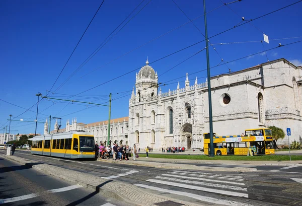 LISBOA, PORTUGAL - 22 DE ABRIL DE 2015: Turistas y ciudadanos que llegan en tranvía amarillo y autobús turístico para visitar el Monasterio de Jerónimos en el barrio de Belem . — Foto de Stock