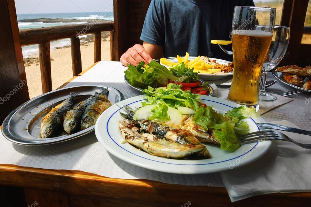 Traditional Portuguese lunch grilled sardines and chicken at restaurant terrace with ocean