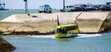 Lizbon, Portekiz - 22 Nisan 2015: Turistlerle gezi amfibi otobüsü Hippotrip yoldan iniyor ve Tagus nehrine giriyor.