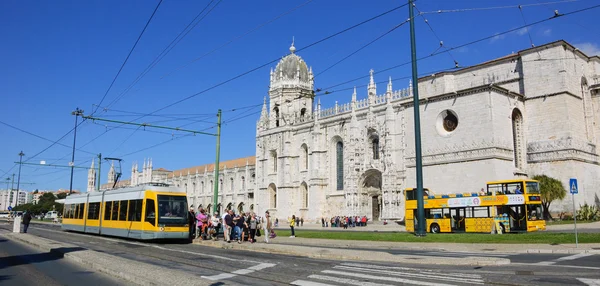LISBOA, PORTUGAL - 22 DE ABRIL DE 2015: Turistas y ciudadanos que llegan en tranvía amarillo y autobús turístico para visitar el Monasterio de Jerónimos en el barrio de Belem . — Foto de Stock