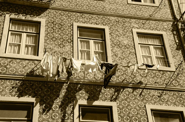 Tipikus régi épület a Lisszabon központjában (Portugália) Kerámia burkolólapok (Azulejos) és a fehérnemű lógott a napon. Évesen fénykép. Szépia. — Stock Fotó
