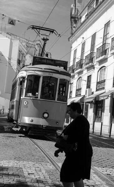 Lisbon, Portekiz - 22 Nisan 2015: Lizbon tarihi merkezinde dolaşan eski bir tramvay önce geçen kimliği belirsiz bir kadın. Bu küçük tramvay Lizbon en tanınan simgeleri biridir. — Stok fotoğraf