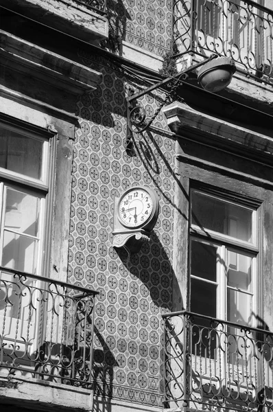 Hodiny a Lucerna typické staré budovy vyzdobené keramickými dlaždicemi (azulejos) v centru Lisabonu (Portugalsko). Stará fotka. Černobílá. — Stock fotografie