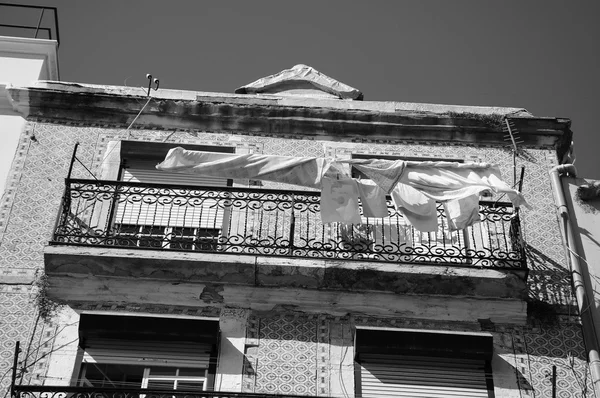 Typical old building in the centre of Lisbon (Portugal) with ceramic tiles (azulejos) and the linen and kitchen towels hanging to dry on the sun. Aged photo. Black and white.