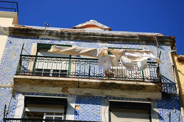 Típico edificio antiguo en el centro de Lisboa (Portugal) con baldosas cerámicas (azulejos) y la ropa de cama y toallas de cocina colgando para secar al sol . — Foto de Stock