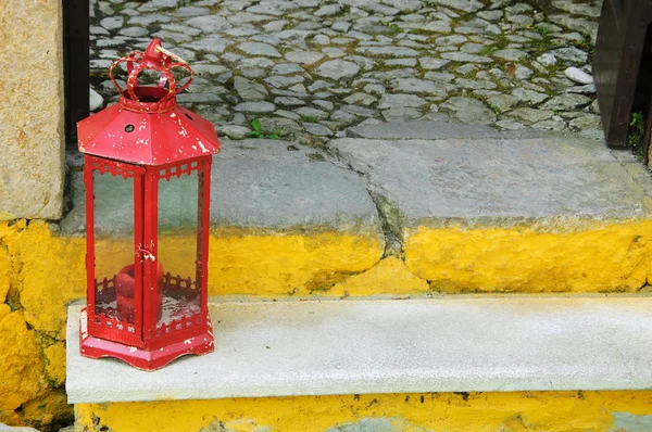 Vintage red lantern with a candle on the steps of typical Portuguese rural house. — Stock Photo, Image