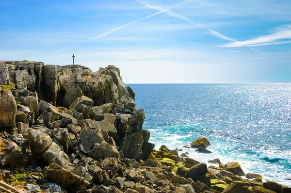 Atravesse o cume rochoso sobre o oceano. Cruze no céu - traço de avião. Peniche, Portugal . — Fotografia de Stock