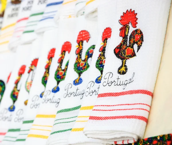 Souvenir towels with embroidery of the Galo de Barcelos (Barcelos Rooster) -  traditional symbol of Portugal - at the street market in Porto (Portugal). Selective focus on the closest towels. — Stock Photo, Image