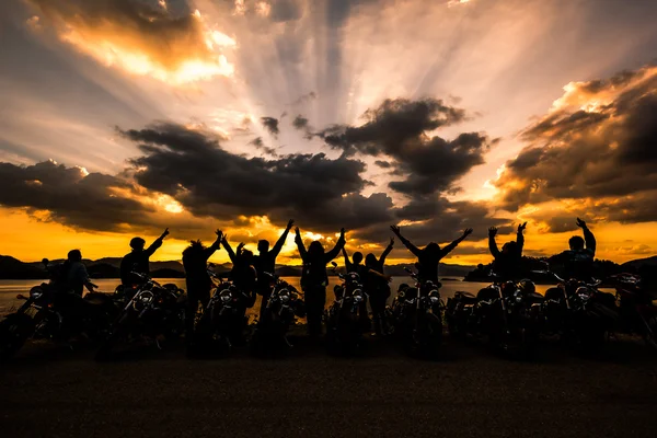 sunse Motosiklet ile ayakta arkadaş grubu silüeti