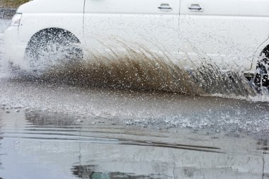 Araba yağmuru su sıçratıyor.