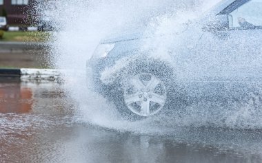 Araba yağmuru su sıçratıyor.