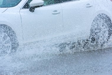 Araba yağmuru su sıçratıyor.