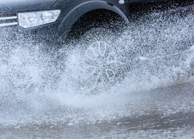 Araba yağmuru su sıçratıyor.