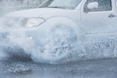 Araba yağmuru su sıçratıyor.