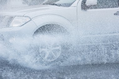 Araba yağmuru su sıçratıyor.