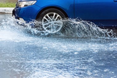 Araba yağmuru su sıçratıyor.