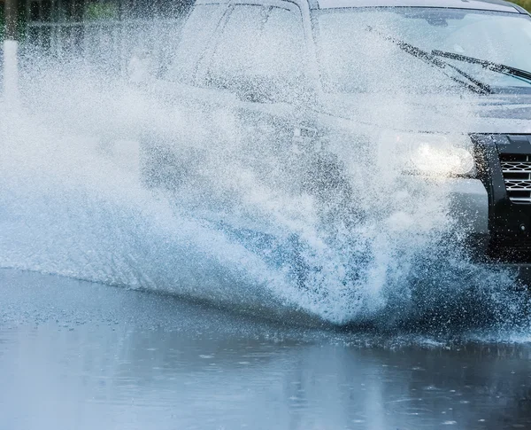 Автомобильная дождевая лужа с брызгами воды — стоковое фото