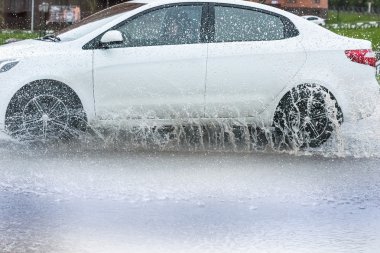 Araba yağmuru su sıçratıyor.