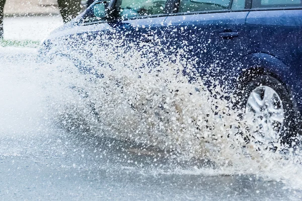 Автомобильная дождевая лужа с брызгами воды — стоковое фото