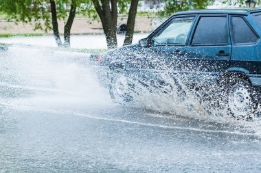 Araba yağmuru su sıçratıyor.