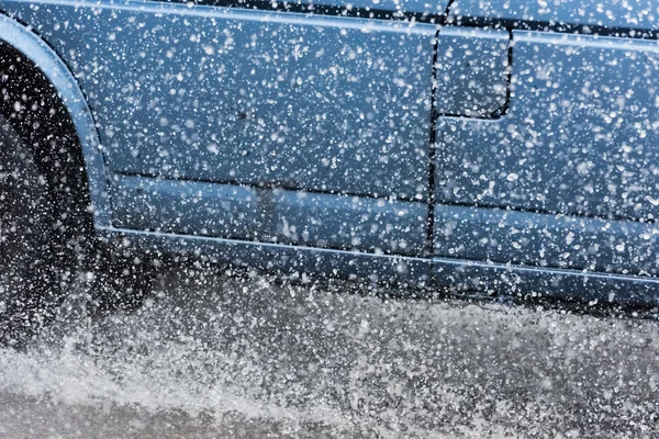 Araba yağmuru su sıçratıyor.