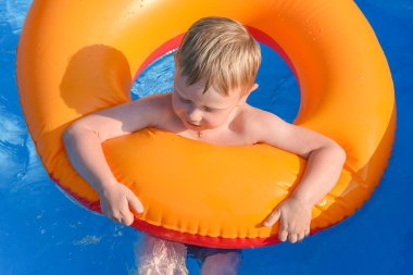 Suda şişirilebilir bir dairede küçük bir çocuk.