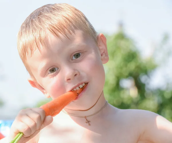 Menino comendo cenoura — Fotografia de Stock